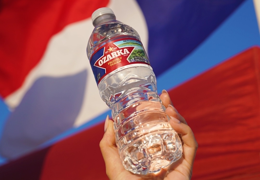 ozarka bottle being held in front of texas flag